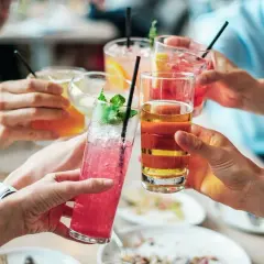 Ludzie wznoszą toasty kolorowymi drinkami. Czy zastanawiasz się, jak kreatyna a alkohol wpływają na formę?